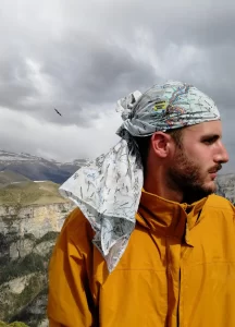 hombre en lo alto de la montaña con el mapa de pañuelo en la cabeza