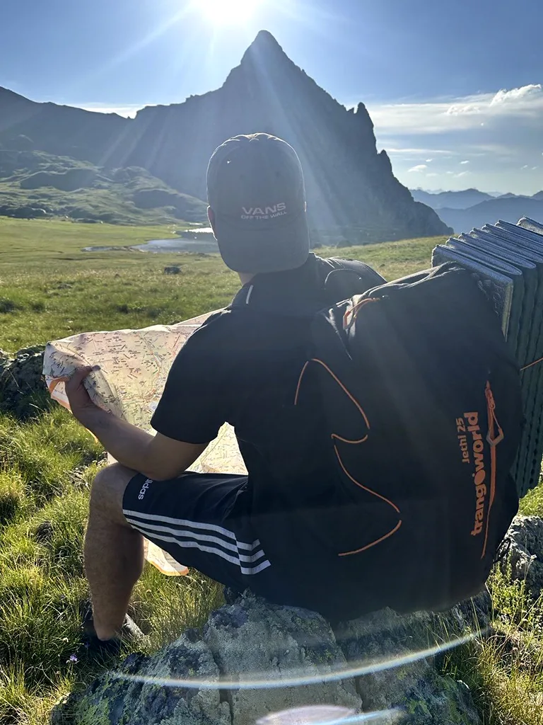 hombre sentado en piedra en la montaña mirando mapa