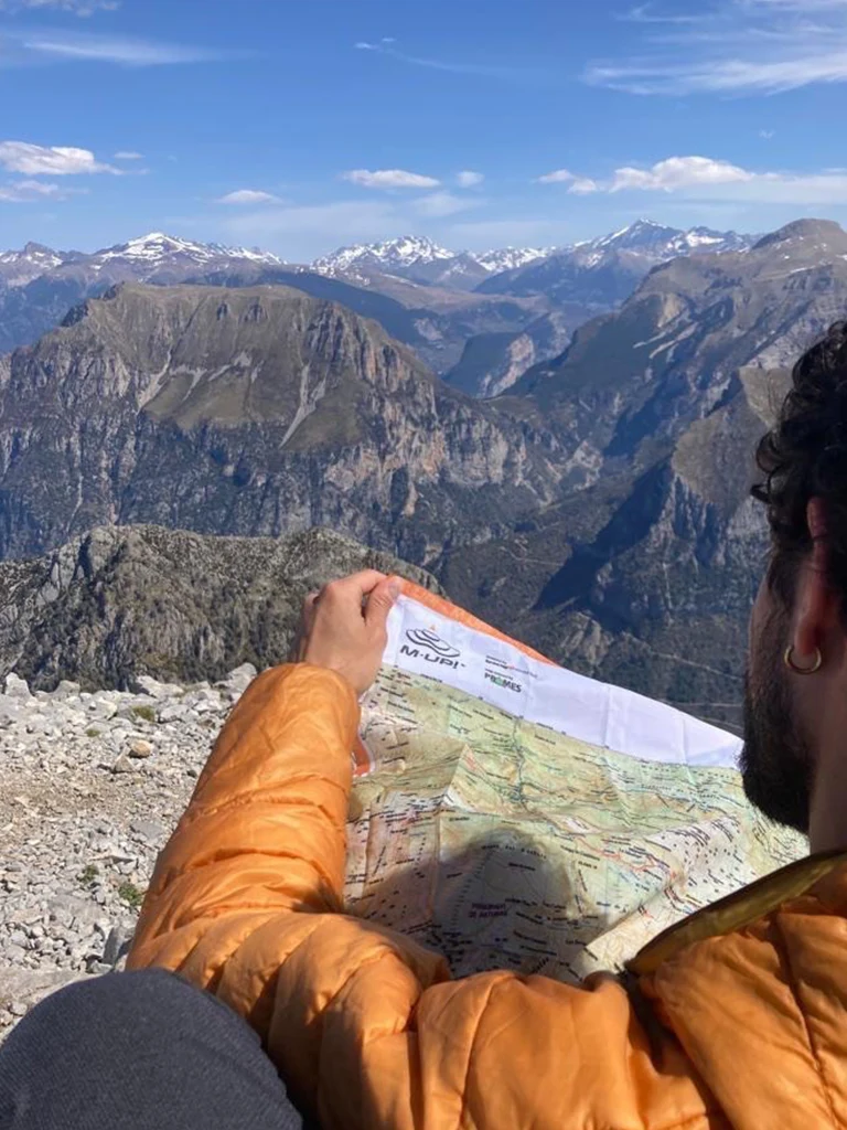 hombre mirando mapa de tela con montañas al fondo